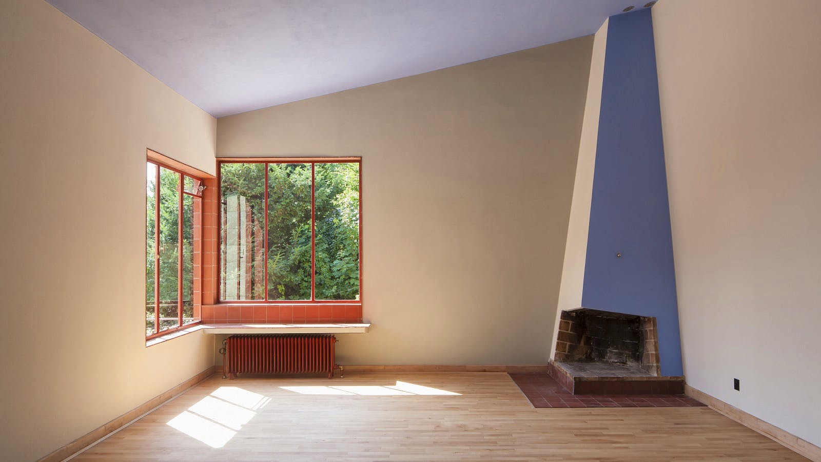 Den store stue midt i huset, der strækker sig i hele husets bredde. Herfra åbner eller lukker skydedøre mod spisestuen og tegnestuen. Stuens store pejs er på den ene side malet i loftets blå farve.