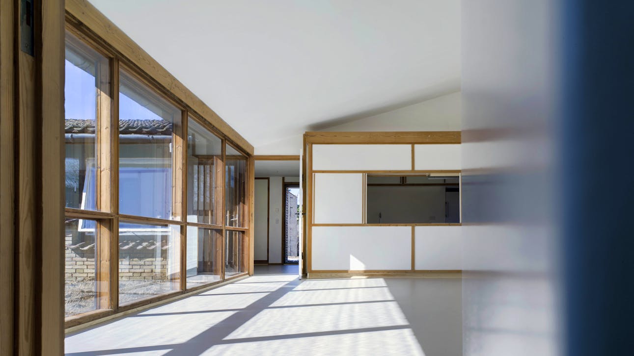 Stuen er husets centrale rum. Loftet skråner mod vinduesvæggen ud til gårdhaven. Vinduerne og ruderne er stadig de originale fra 1960.