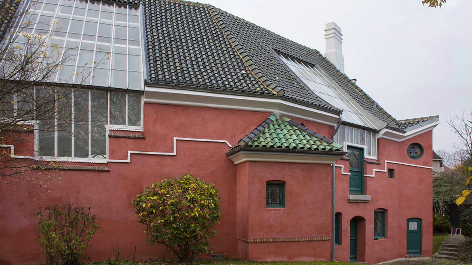 J.F. Willumsens ateliervilla set fra haven, hvor atelierets vinduer strækker sig op i tagfladen.