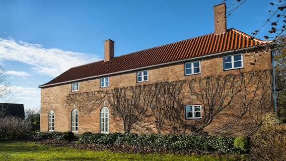 Kay Fiskers landsted set fra havesiden, hvor den oprindelige klatreplante har overlevet restaureringen og nu igen vokser op ad murværket.