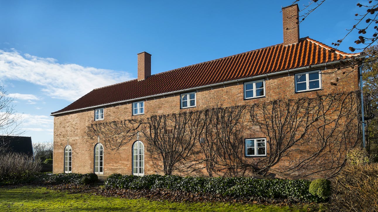 Kay Fiskers landsted set fra havesiden, hvor den oprindelige klatreplante har overlevet restaureringen og nu igen vokser op ad murværket.