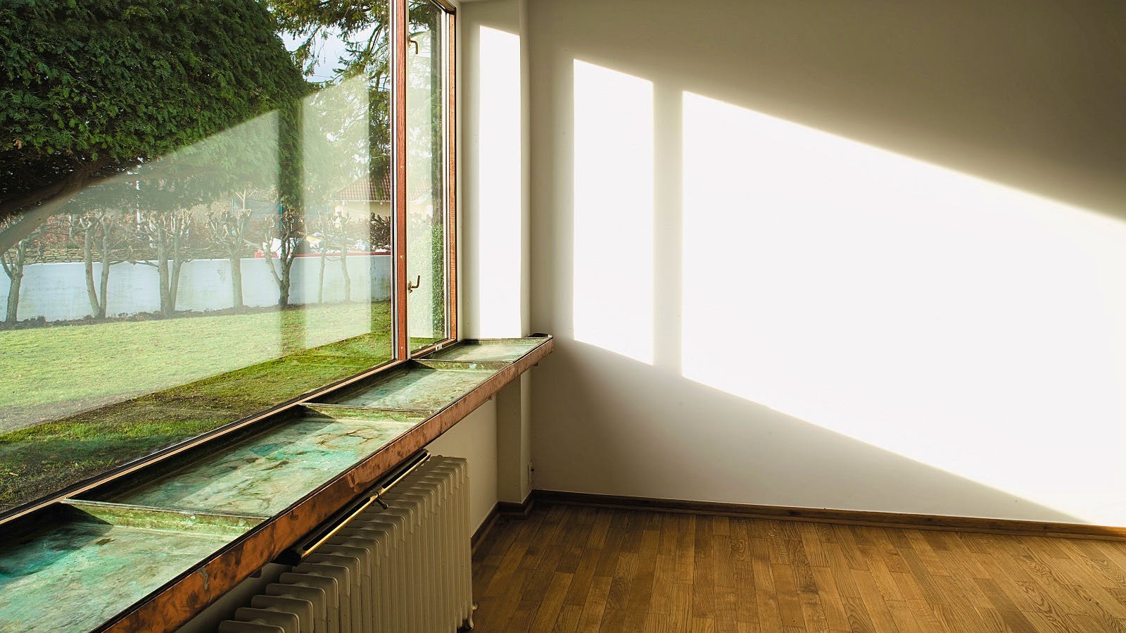 Langt vinduesparti med plantekasser i kobber, udsigt til haven.