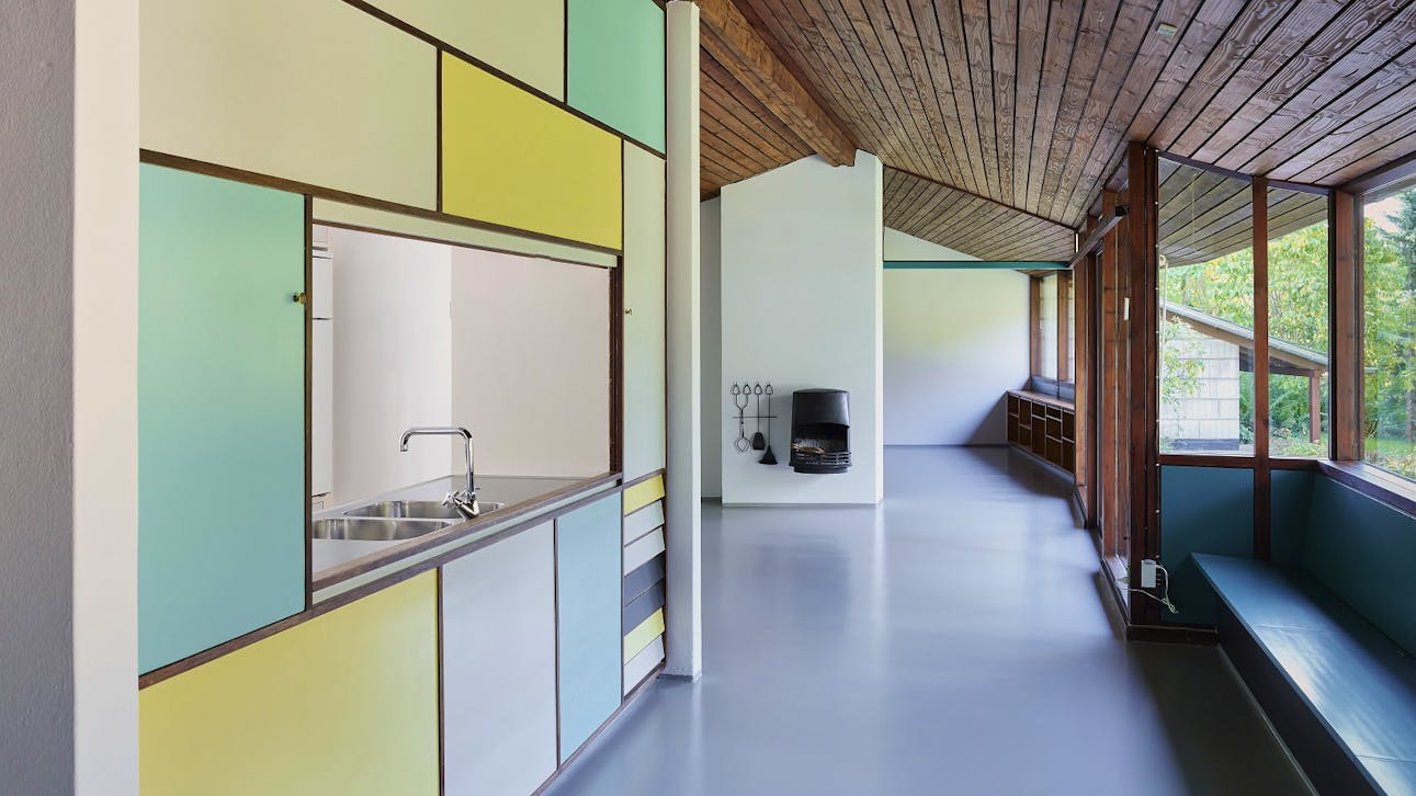 De farvede felter i køkkenet er skabe og skuffer, som kan åbnes fra begge sider, hvilket var praktisk, når der skulle dækkes bord og vaskes op.