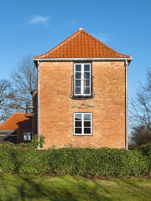 Gavl på landsted tegnet af Kay Fisker med rødt tegltag, murstensfacade og med en fransk altan.