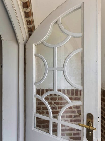 Hvid entredør med glas og buede sprosser i Havnemesterboligen, Skagen.