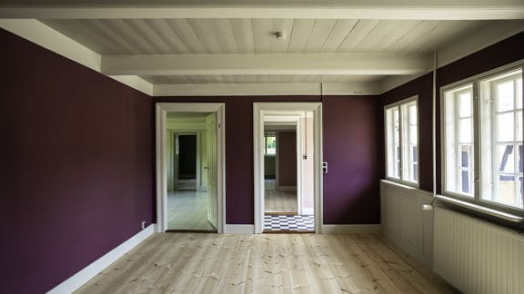 Lyst rum med lyst trægulv, vægge i lilla og hvidt træloft med kig ind til andre rum.