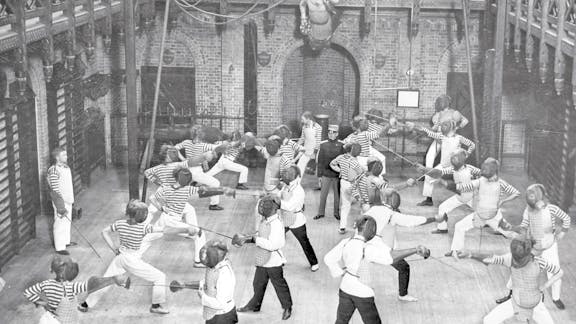 Historisk billede af skolebørn, der øver fægtning i den store sal.