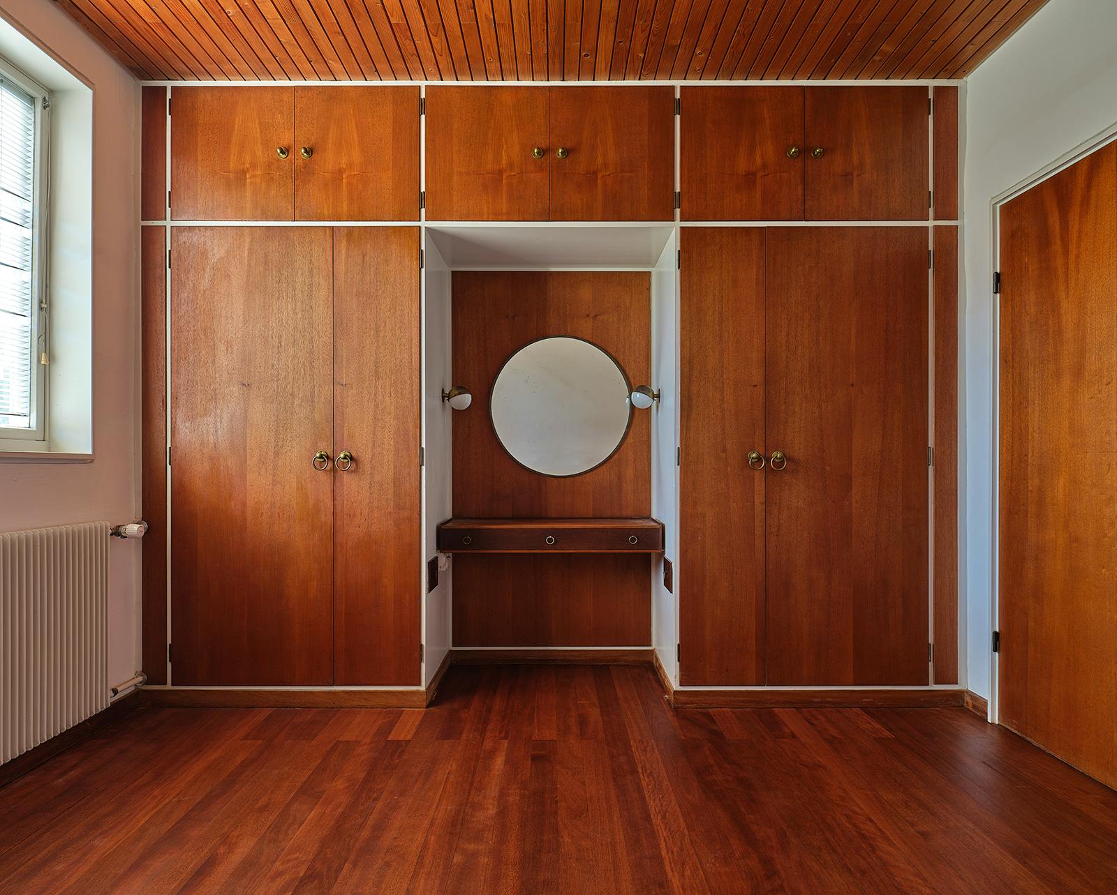 Skabsparti i Vilhelm Lauritzens eget hus med indbyggede skabe i varme træsorter og integreret sminkebord.
