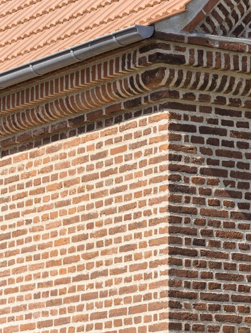 Murdetalje af Havnemesterboligen i Skagen med røde teglsten, gesims og tegltag.