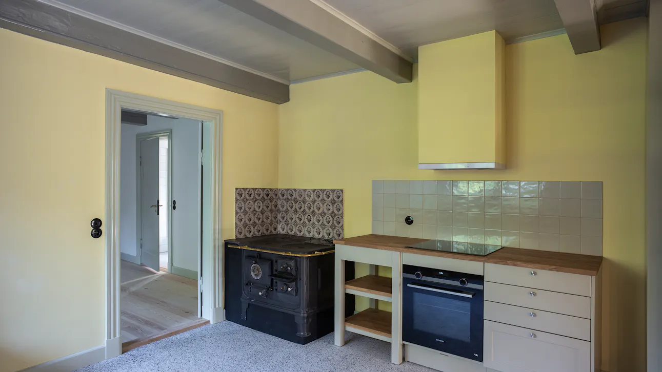 I køkkenet mødes gammelt og nyt: Støbejernskomfur fra 1800-tallet står side om side med moderne køkkenløsninger.