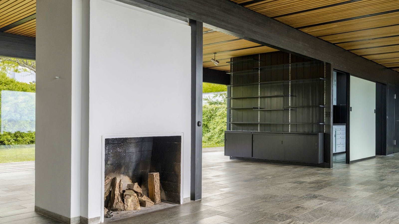 Stuen i Halldor Gunnløgssons eget hus med et grå-blåt marmorgulv, hvid pejs og en sort træreol. 