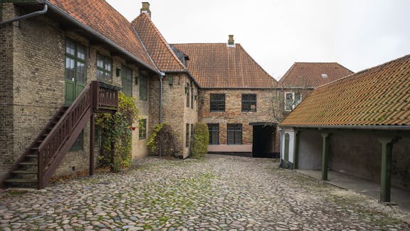 Gården med pigsten, udhus og trappe. Porten til gaden ses i baggrunden.