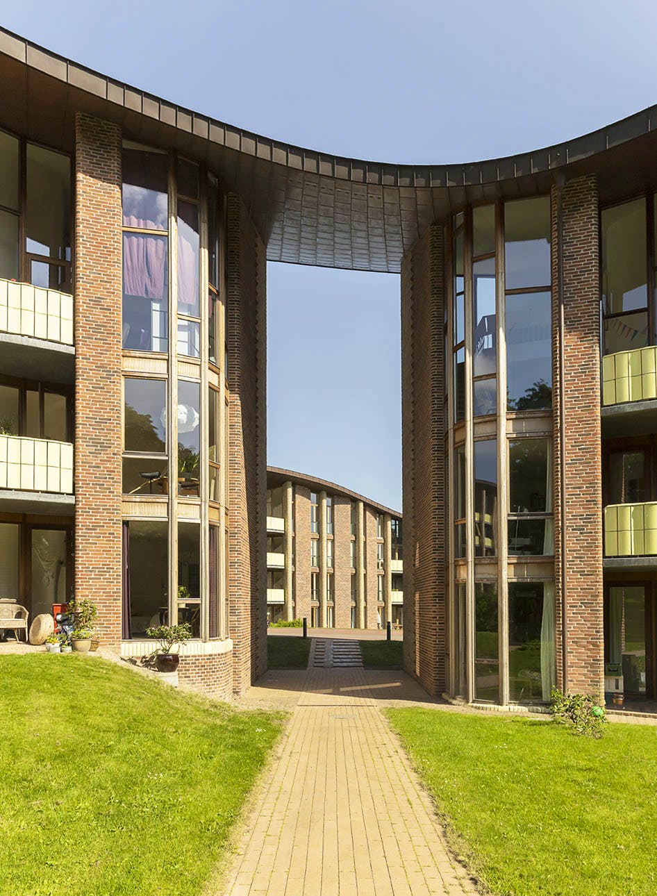 Murstensbygningerne i Bispebjerg Bakke forbindes af en port med buet kobbertag og store vinduespartier.