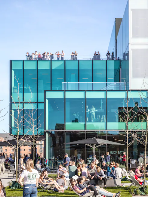 Folk nyder solen foran caféen ved BLOX.