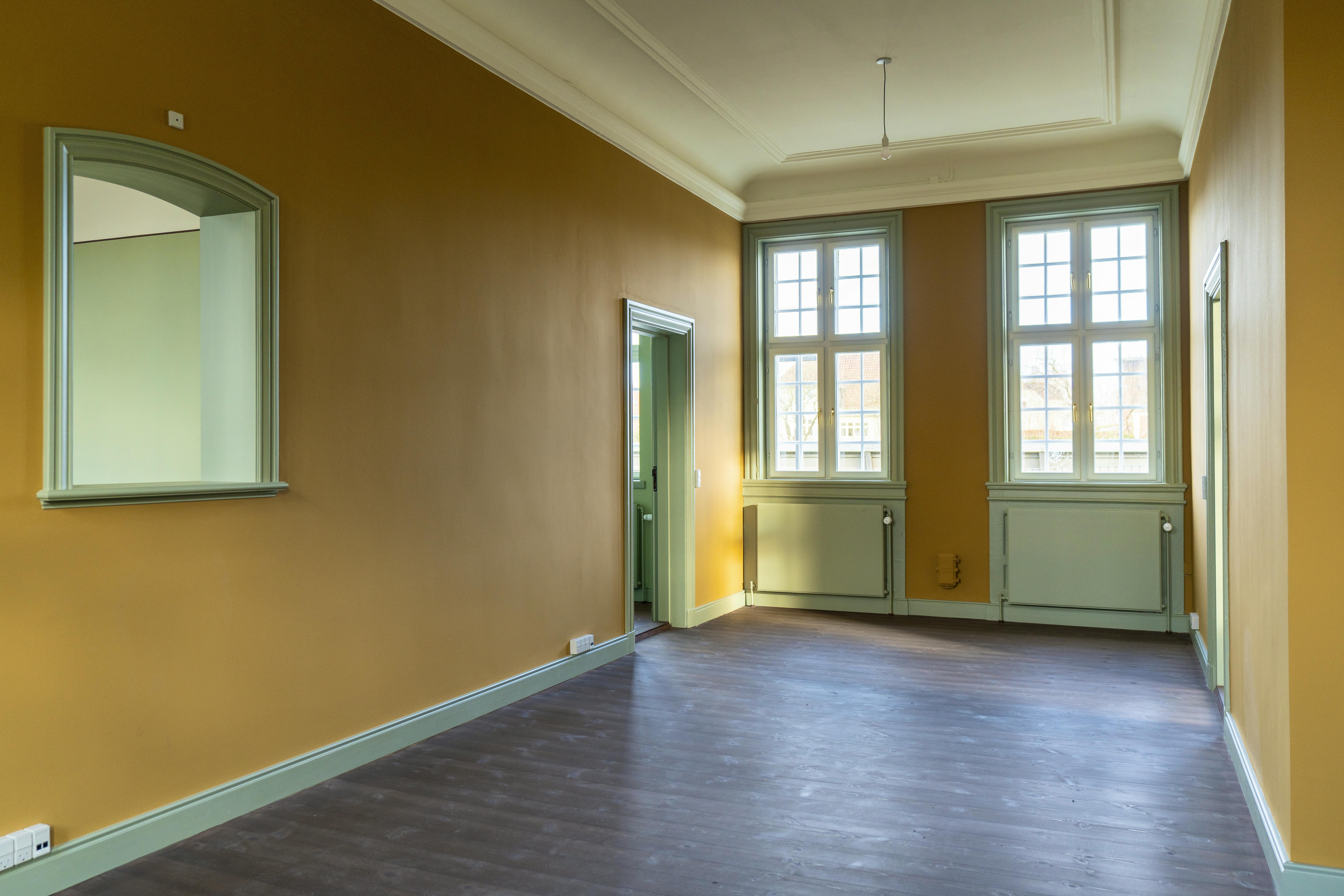 Gult billetkontor med grønne karme og vinduer.