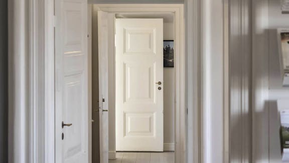 Kig gennem hvide fyldningsdøre i Havnemesterboligen i Skagen.