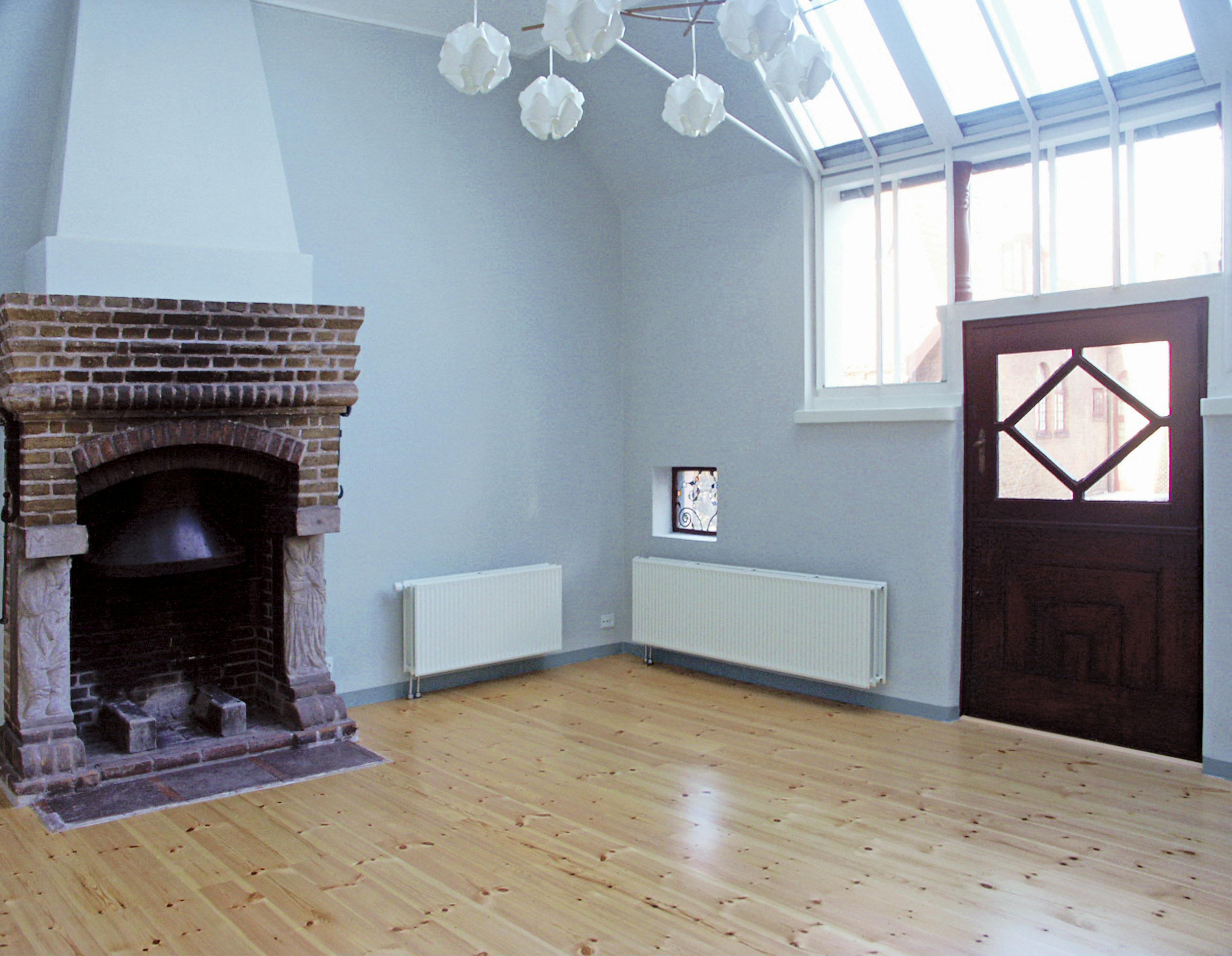 Det lille atelier i J.F. Willumsens ateliervilla har en murstenspejs og et stort vinduesparti, der strækker sig op i loftet.