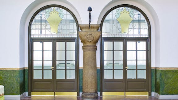 Dørparti i Rosenhusets hall med farvet glas og granitsøjle i midten.