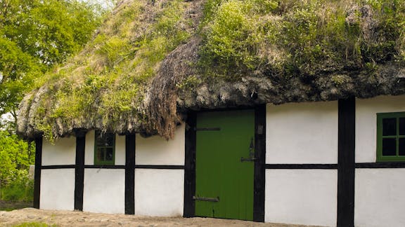 Facade på Kalines tanghus på Læsø med grønt bindingsværk, tangtag og grøn dør.