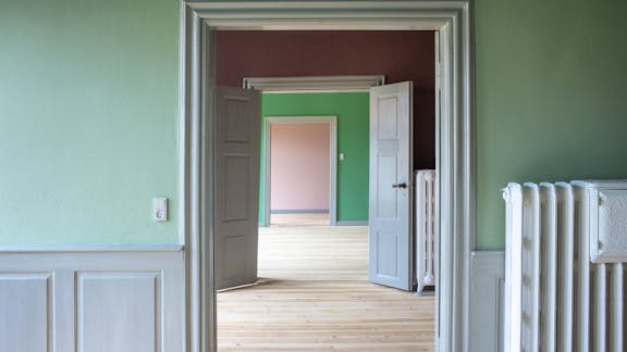 Kig gennem flere stuer med forskellig farvesætning og lyse trægulve i Marcussens Gård.