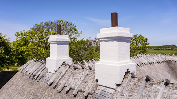 Skorstenene på Højgaarden er enkelt udformet og hvidkalkede med let profilerede gesimser.