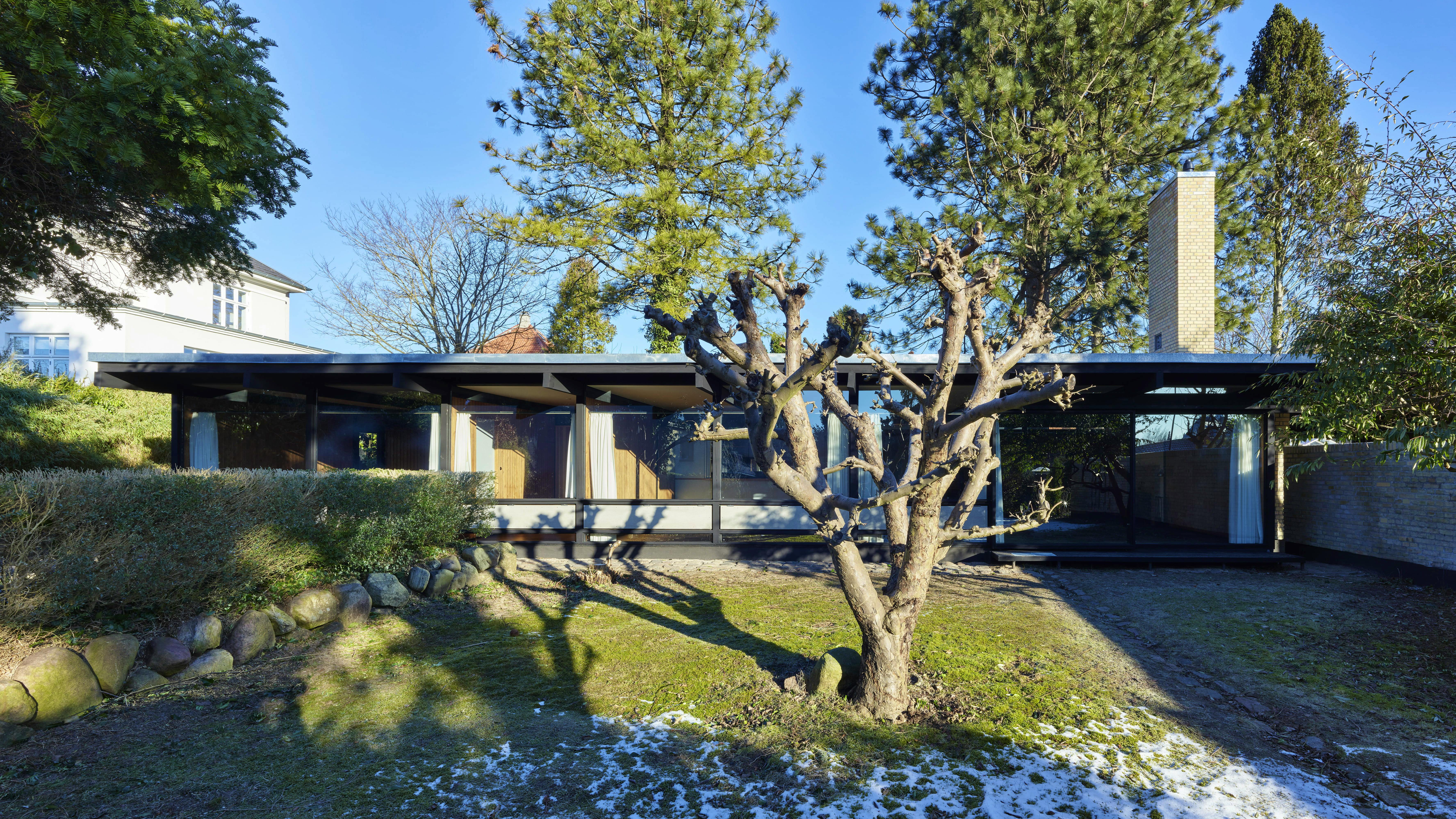 Facade mod syd hvor den gulve horisontale mur og den vertikale skorsten skyder sig ud og op.