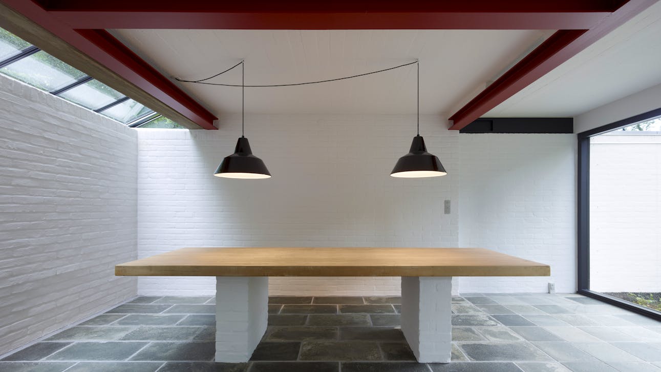 Det nagelfaste spisebord. Accentueringen af konstruktion ses tydeligt i spisestuen, hvor jernbjælkerne er malet røde.