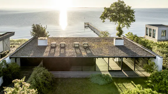 Halldor Gunnløgssons eget hus set oppe fra. Huset ligger ned til vandet og har adgang til en badebro. 