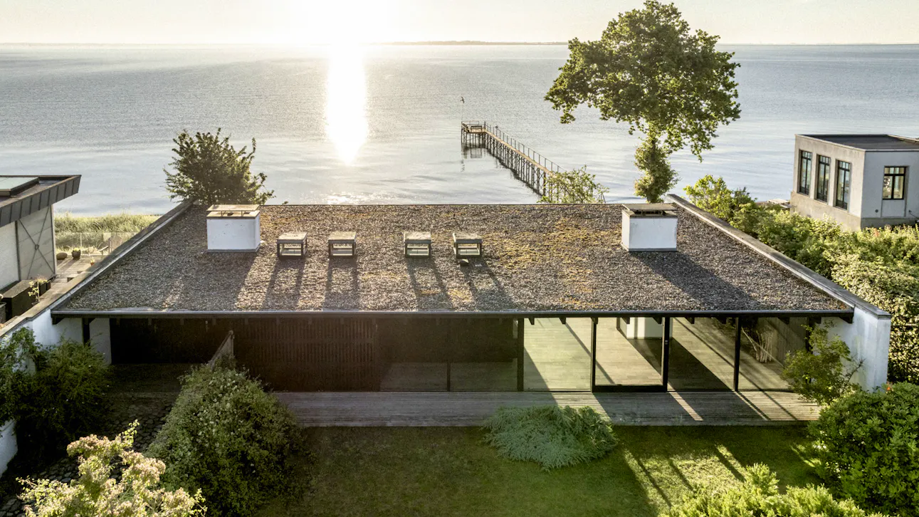 Halldor Gunnløgssons eget hus set oppe fra. Huset ligger ned til vandet og har adgang til en badebro. 