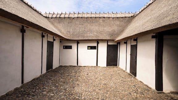 Gårdrummet på Højgaarden er omgivet af fire længer med hvidkalkede mure, sort træværk og stråtækte tage.