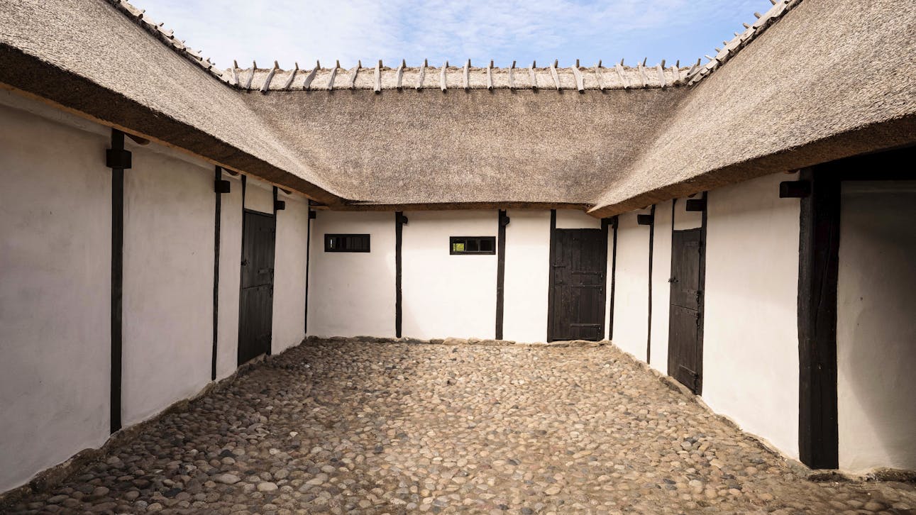 Gårdrummet på Højgaarden er omgivet af fire længer med hvidkalkede mure, sort træværk og stråtækte tage.