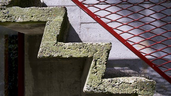 PH's hus er opført i betonelementer - det gælder også den spinkle trappe til bagdøren i gavlen mod vejen. Gitterværket i jern er malet i blymønjerød.