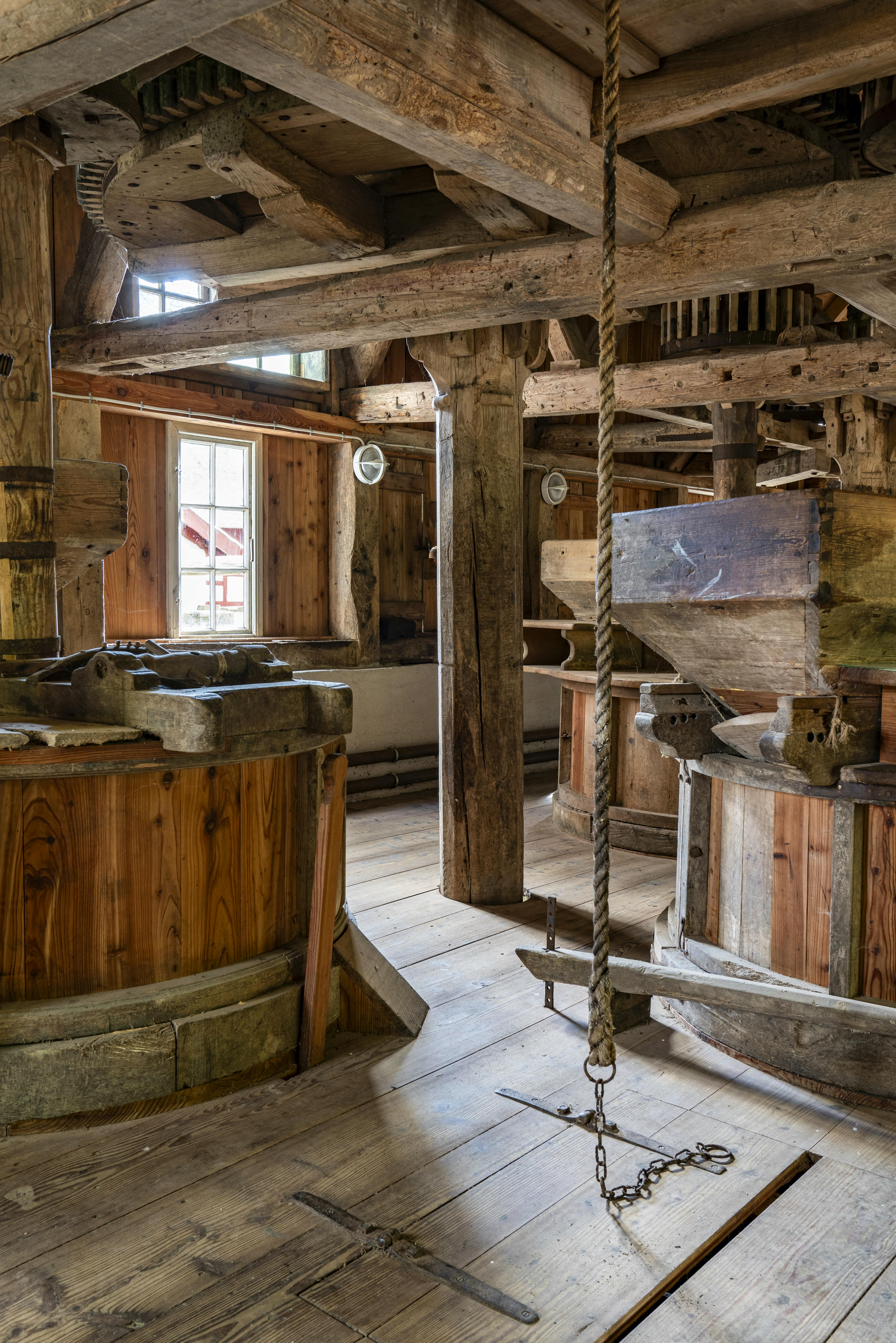 Inde i mølleriet på Gammelby Mølle med kværne, tandhjul og hejseværk i træ.
