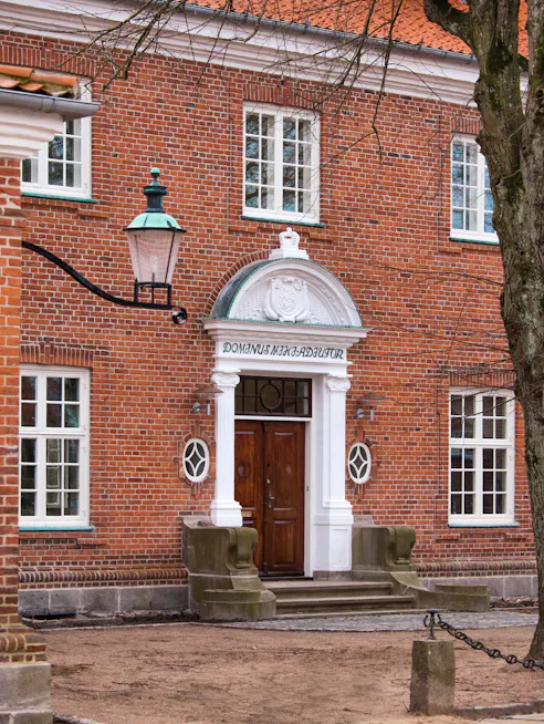 Hovedindgang og facade på Amtmandsboligen i Hjørring med inskription og klassiske detaljer.