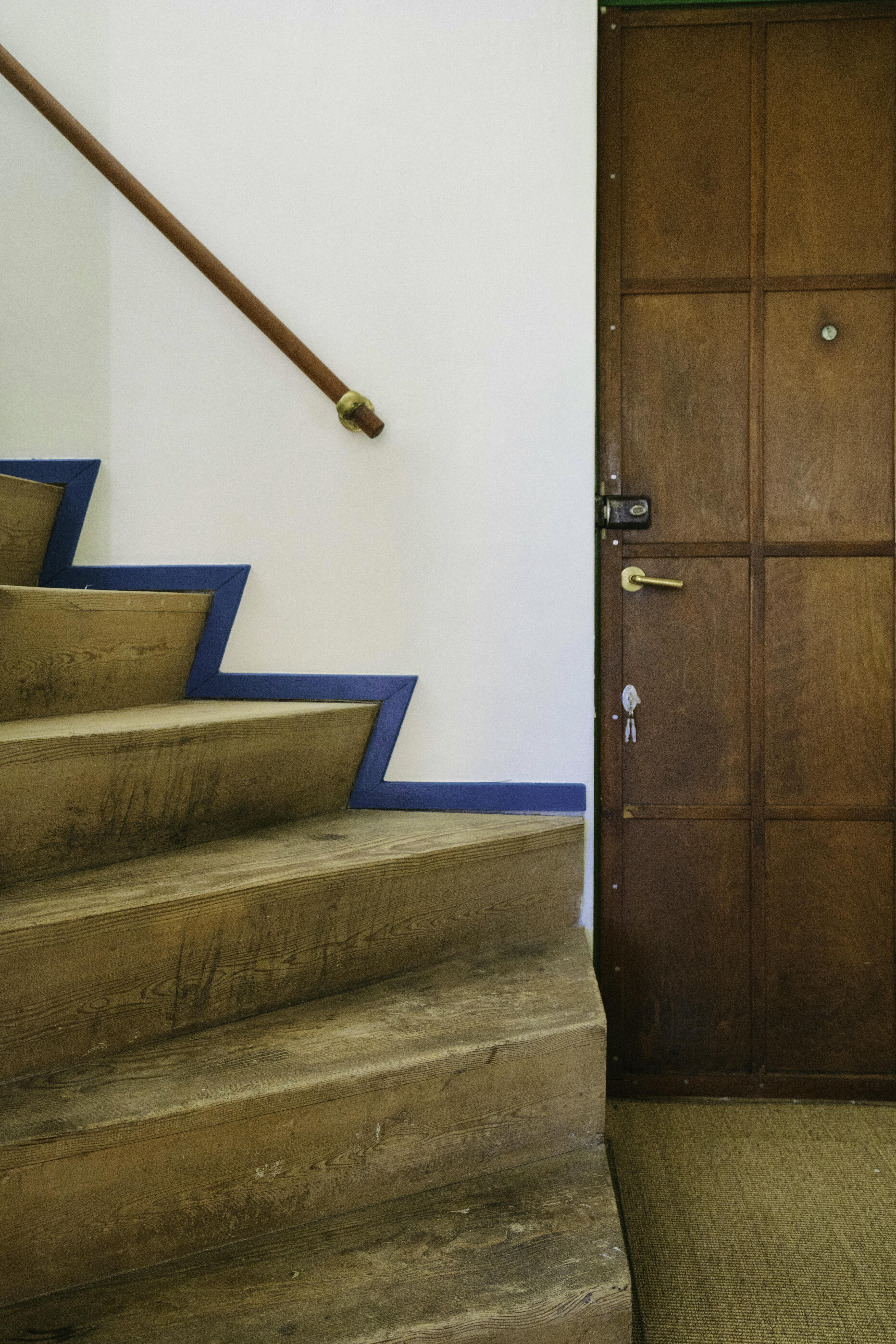 Indgangsparti i Viggo Møller-Jensens eget hus med trætrappe, blåmalet trappekant, messinggreb og dør i mørkt træ.
