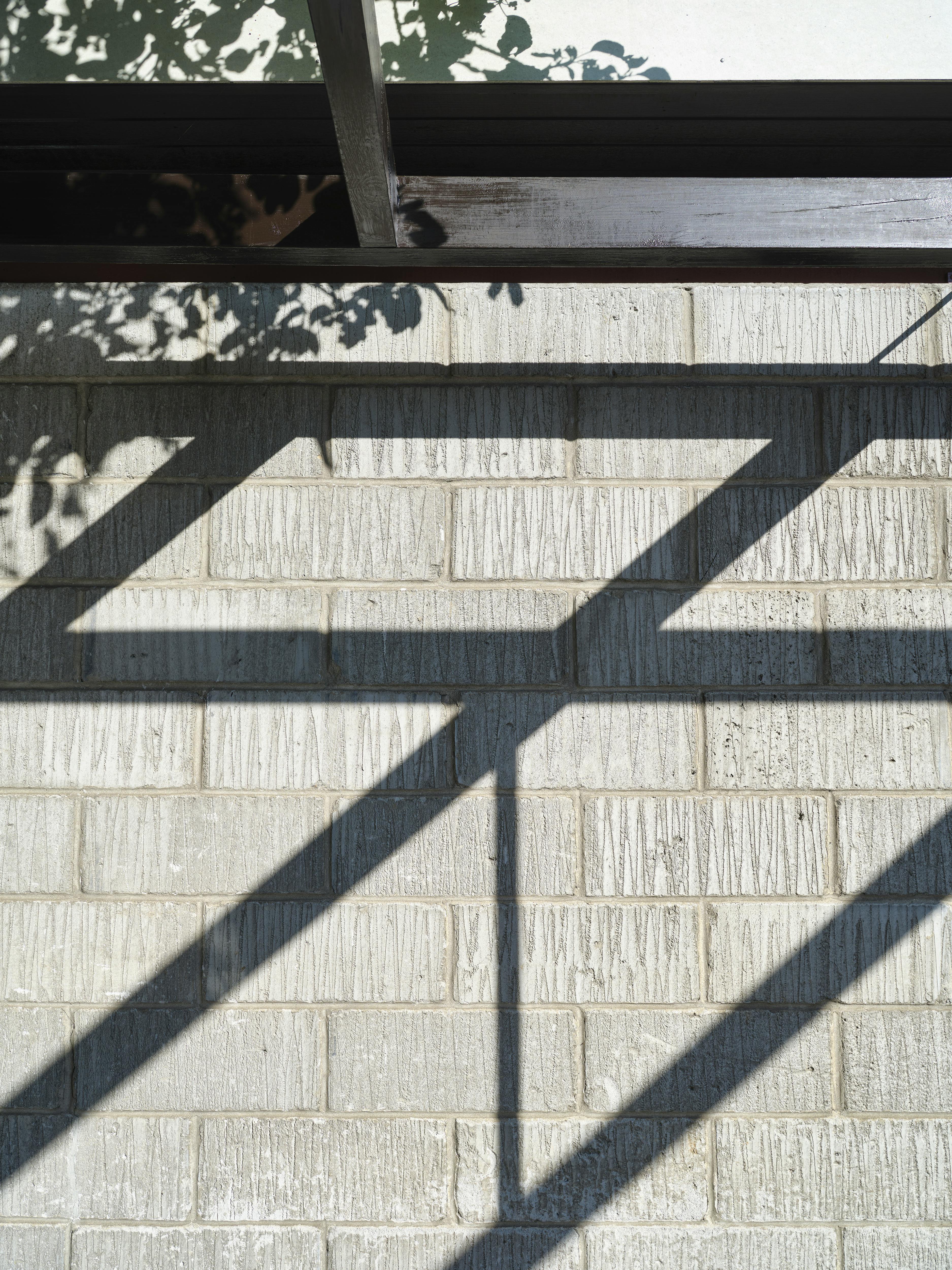 Skygger fra espalier danner mønster på gasbetonmuren.