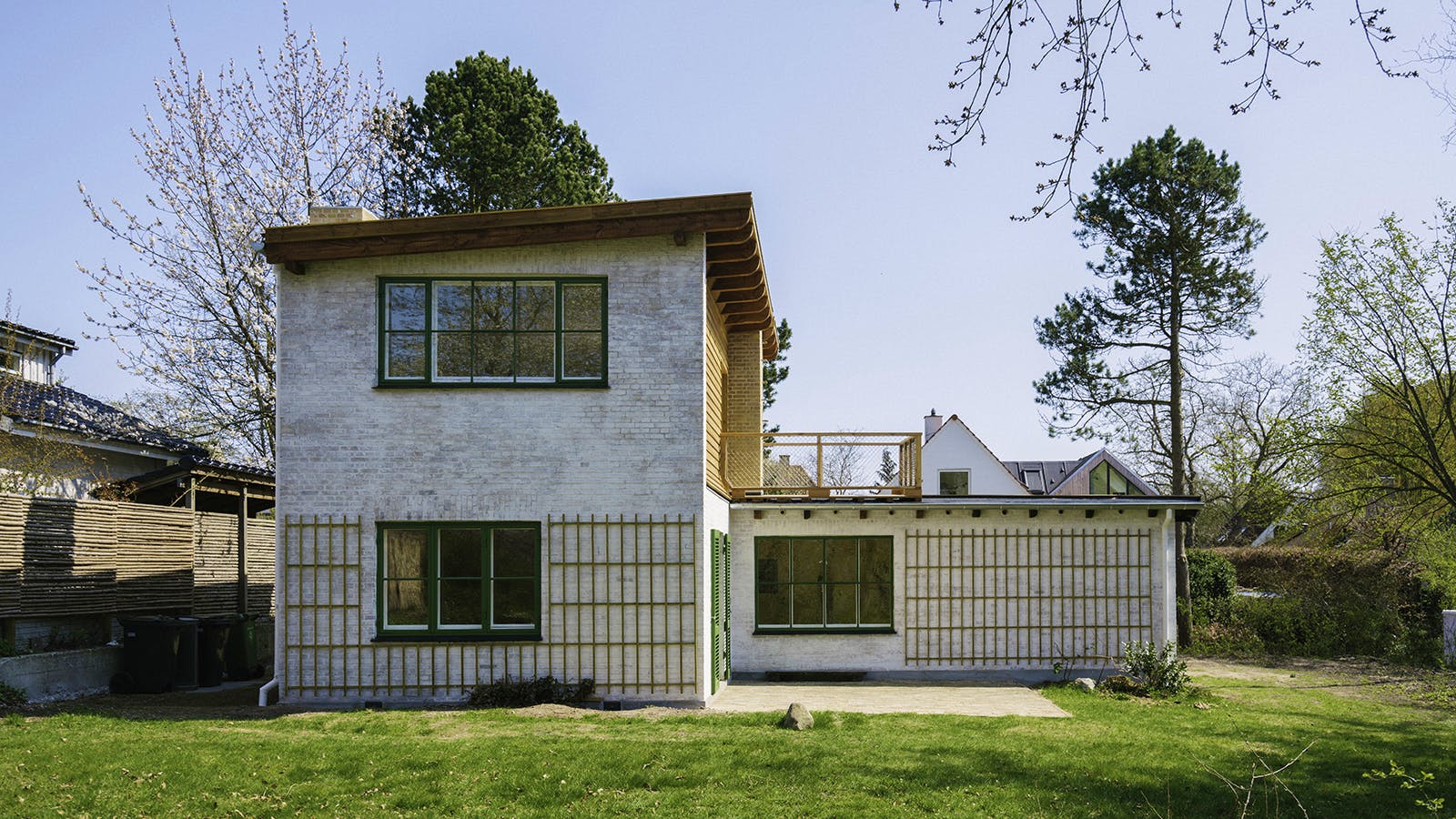 Havefacade på Viggo Møller-Jensens eget hus med hvidmalet murværk, grønne vinduesrammer, espalier og altan med træværn.