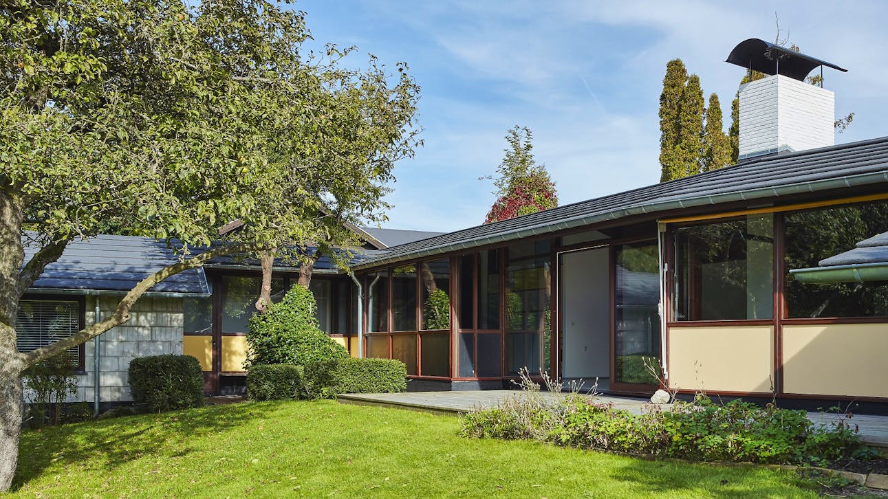 Skorstenen er husets eneste element i mursten. Facadens transparente udtryk får næsten skorstenen til at fremstå som en skulptur, huset er bygget op omkring.