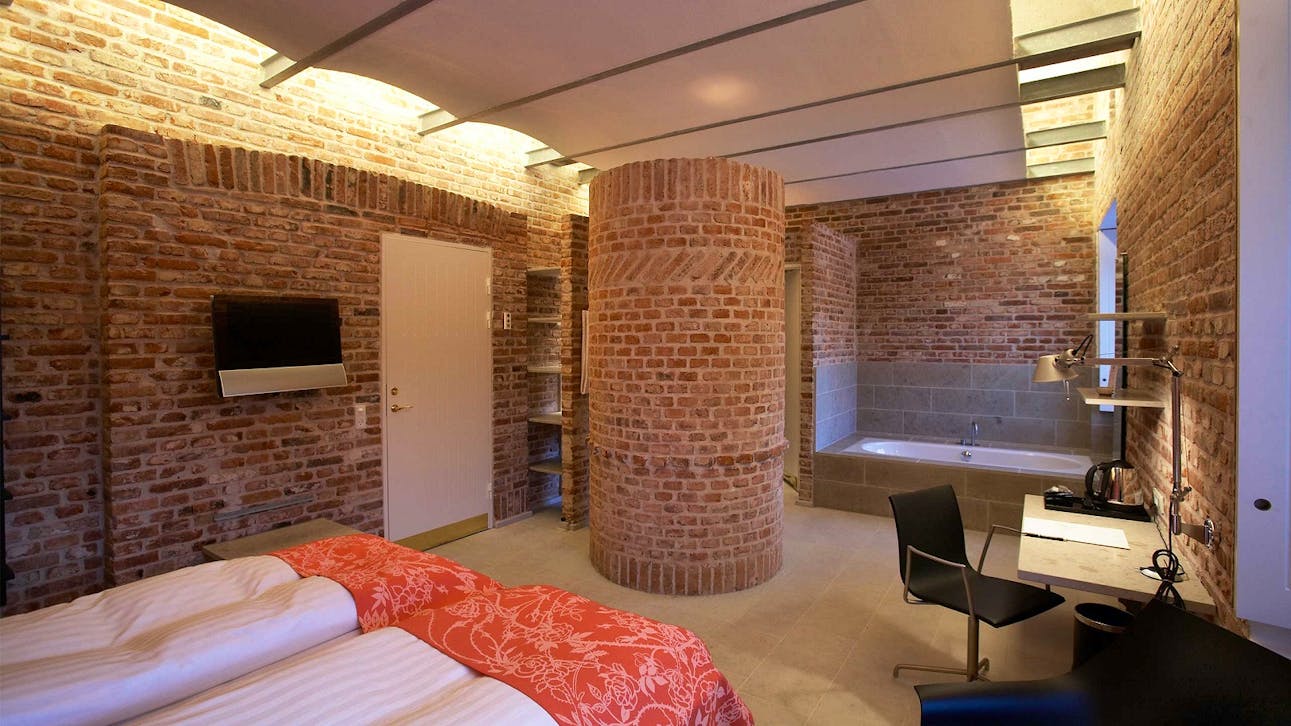 Værelse i den tidligere kostald på Hindsgavl Slot med frit murværk og badekar.