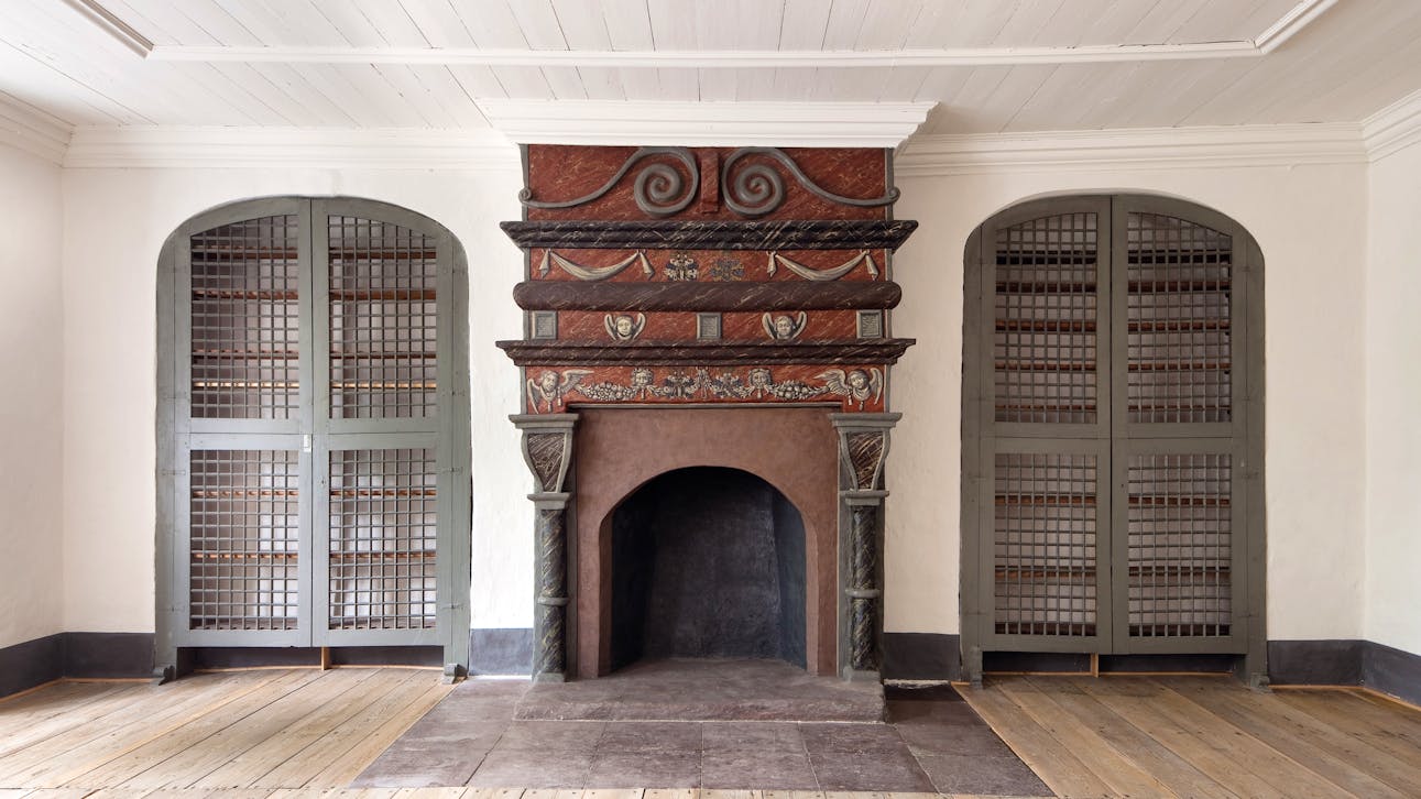 Karan Brahes berømte bibliotek stod i disse indbyggede reoler. Pejsen fremstår med renæssancebemaling og er fra kongens tid som ejer af huset.