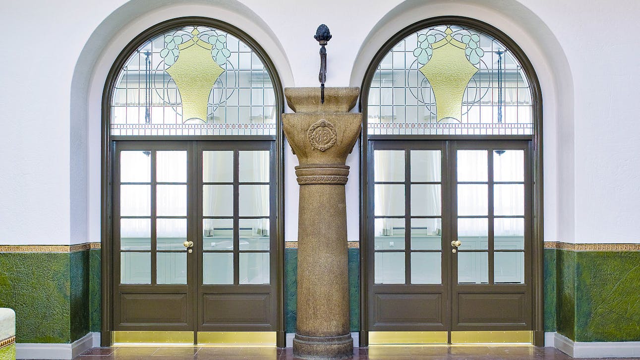 Dørparti i Rosenhusets hall med farvet glas og granitsøjle i midten.