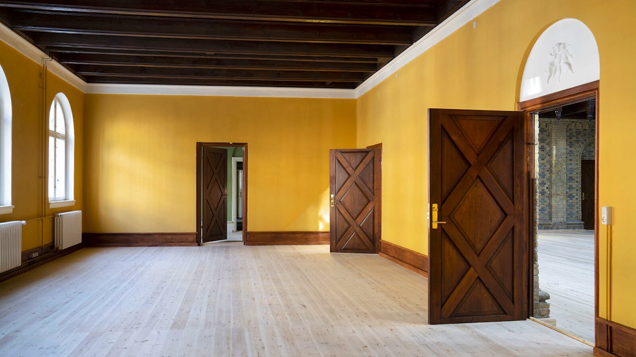 Gult rum med åbne døre og kig til aulaen i Søetatens Pigeskole.