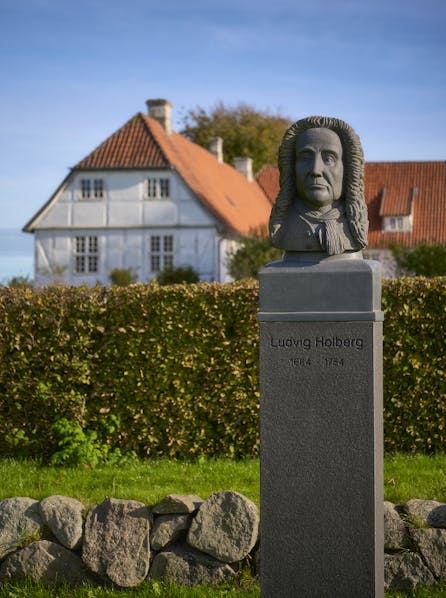 Statue af Ludvig Holberg med bygningen i baggrunden